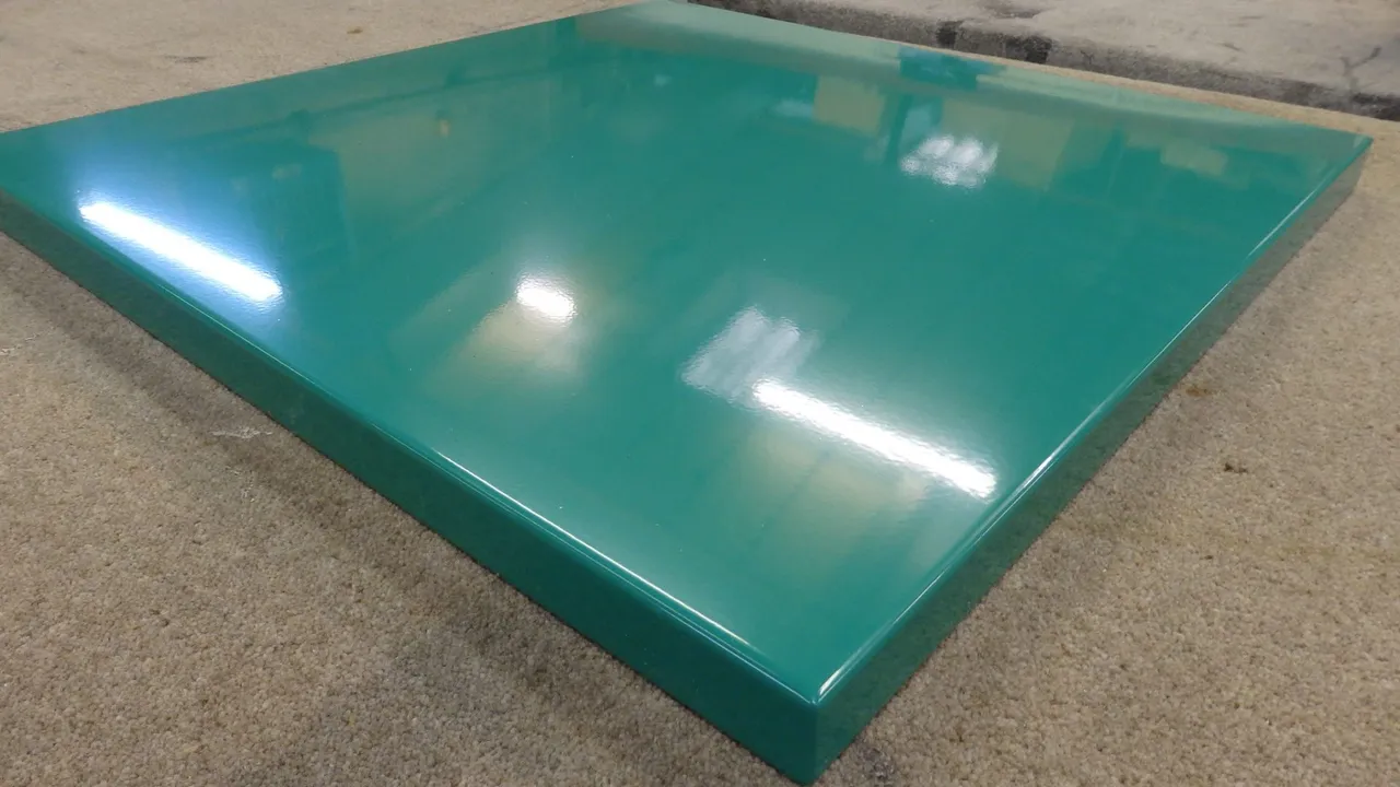 A glossy green metal surface reflecting overhead lights