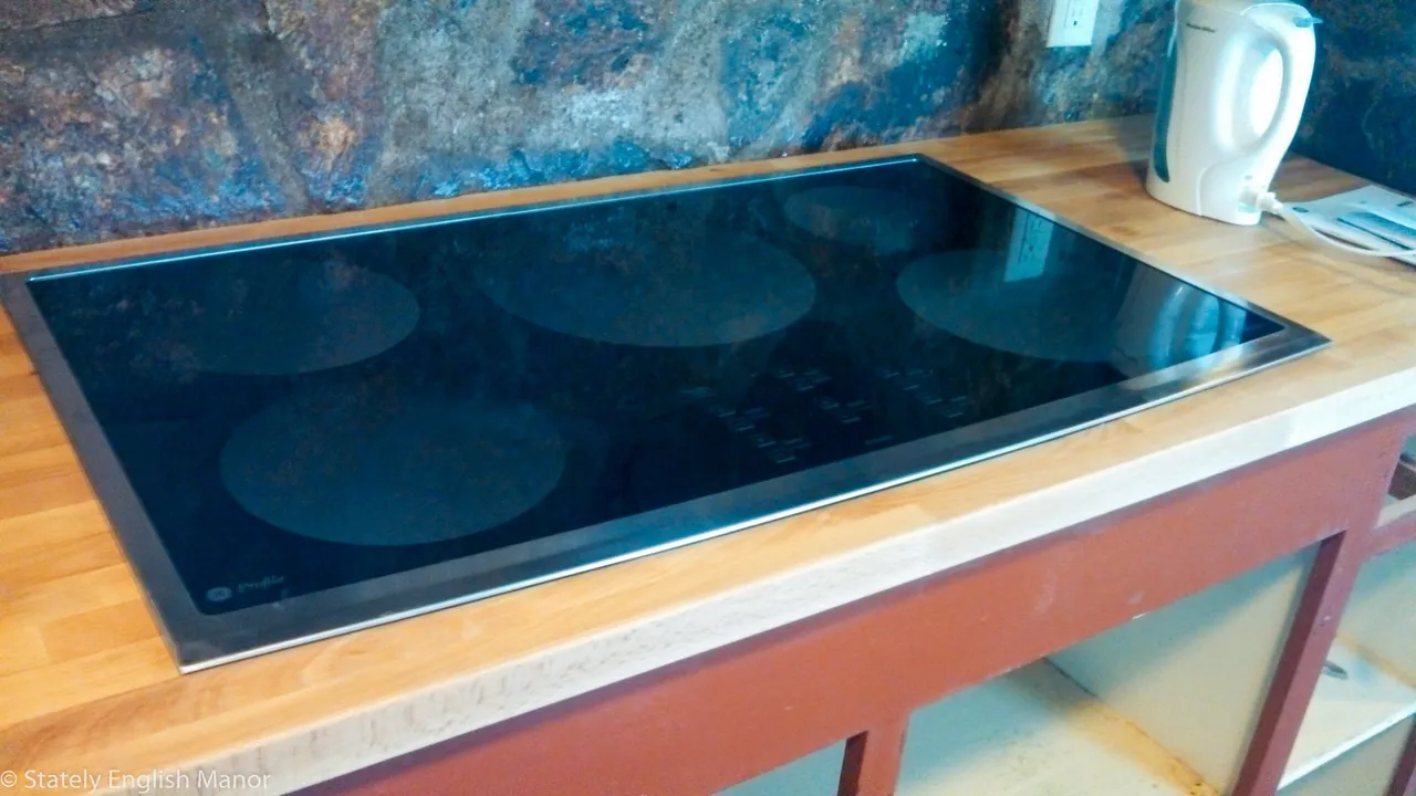 A flat black glass cooktop set into a kitchen counter
