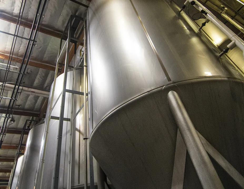 A large brushed stainless steel storage tank inside a factory