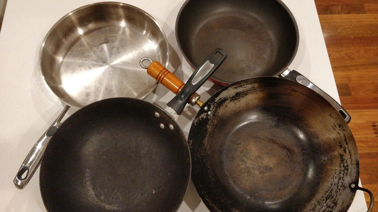Stainless steel and dark-finished pans arranged together