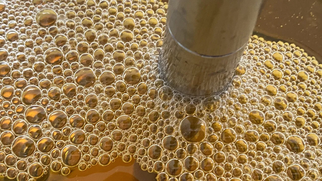 Golden cleaning bubbles clustered around a metal tube