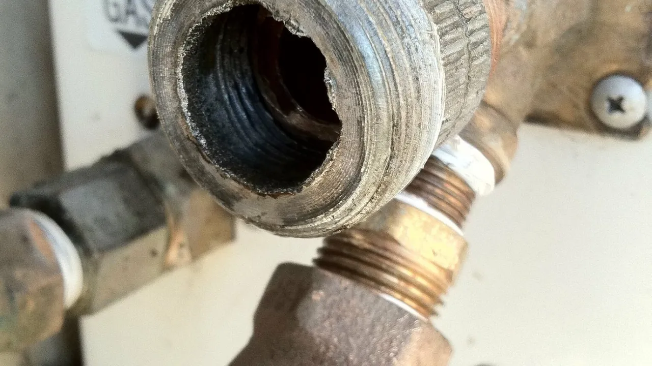 Close view of a threaded metal fitting beside copper and steel pipes