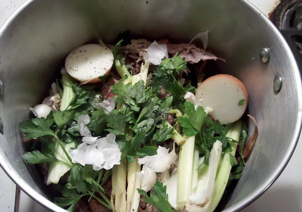Fresh vegetables and herbs inside a stainless steel stockpot