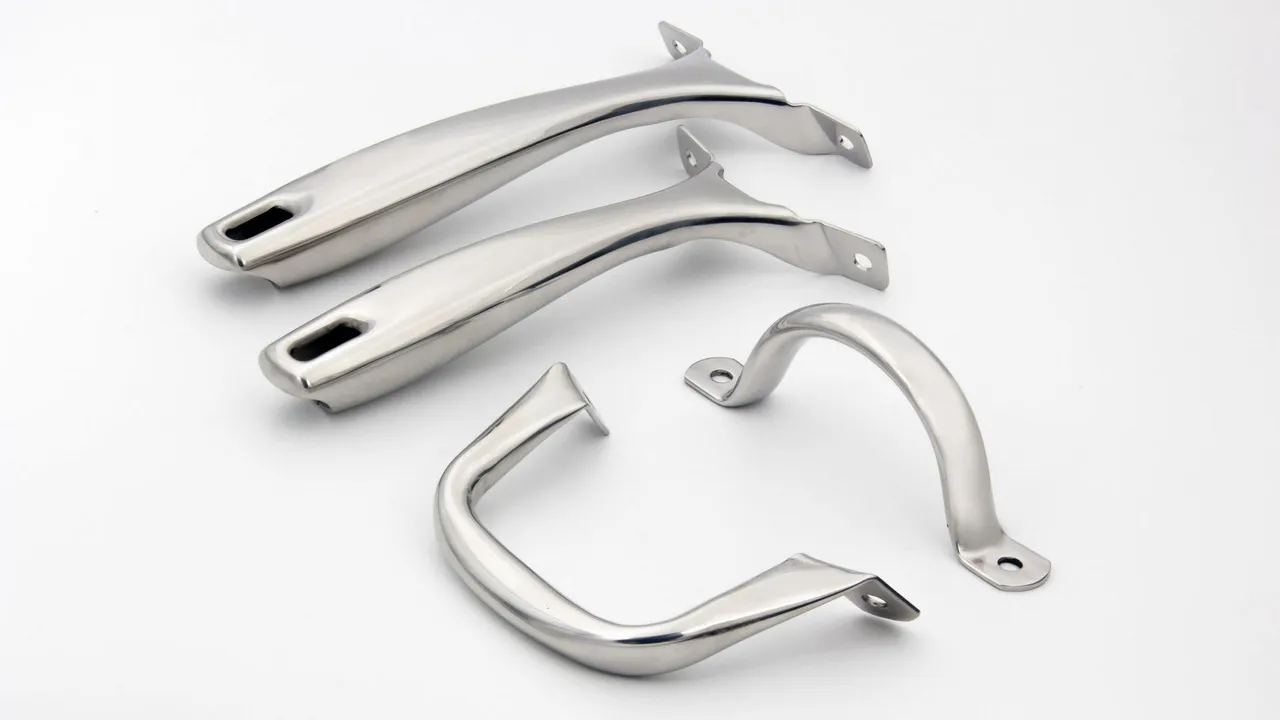 Four polished stainless steel cookware handles on a white surface