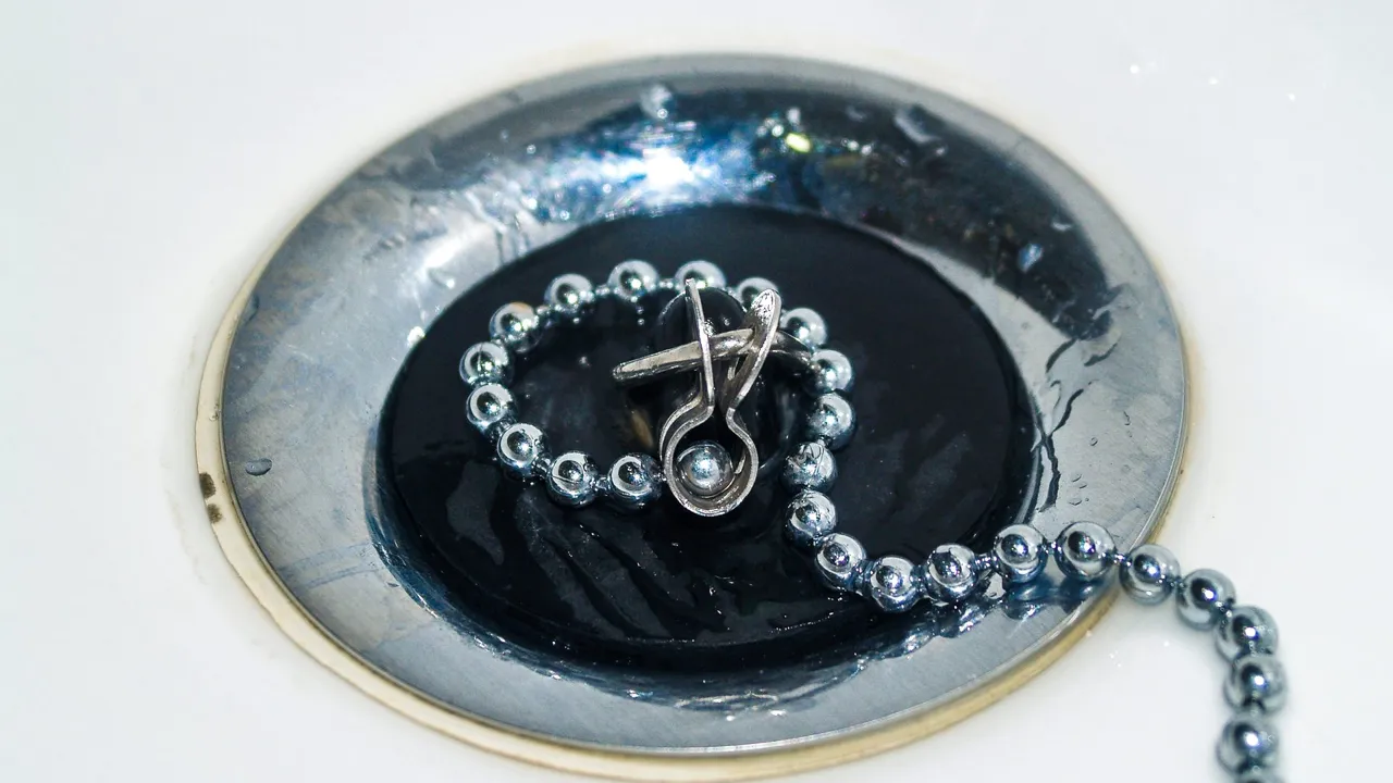 A polished stainless steel sink drain and chain