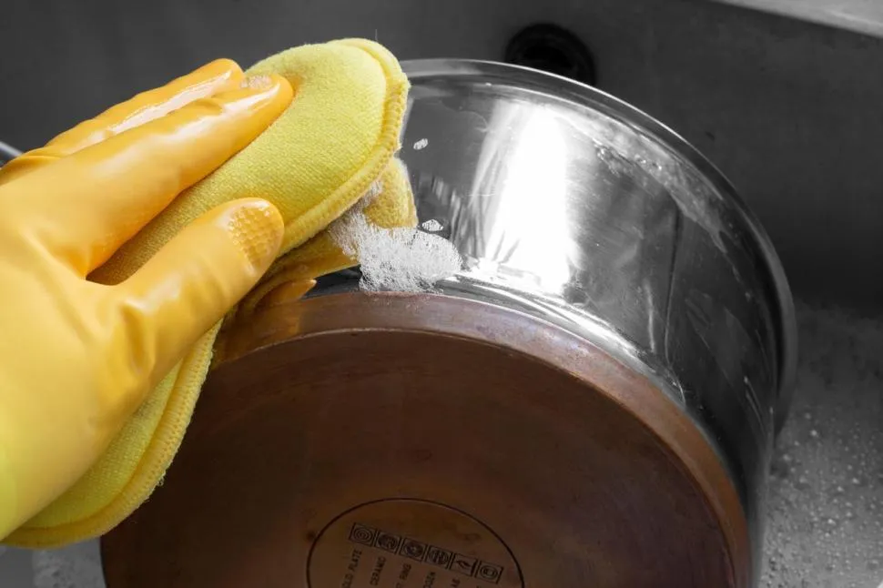 Stainless steel cookware being washed in a kitchen sink