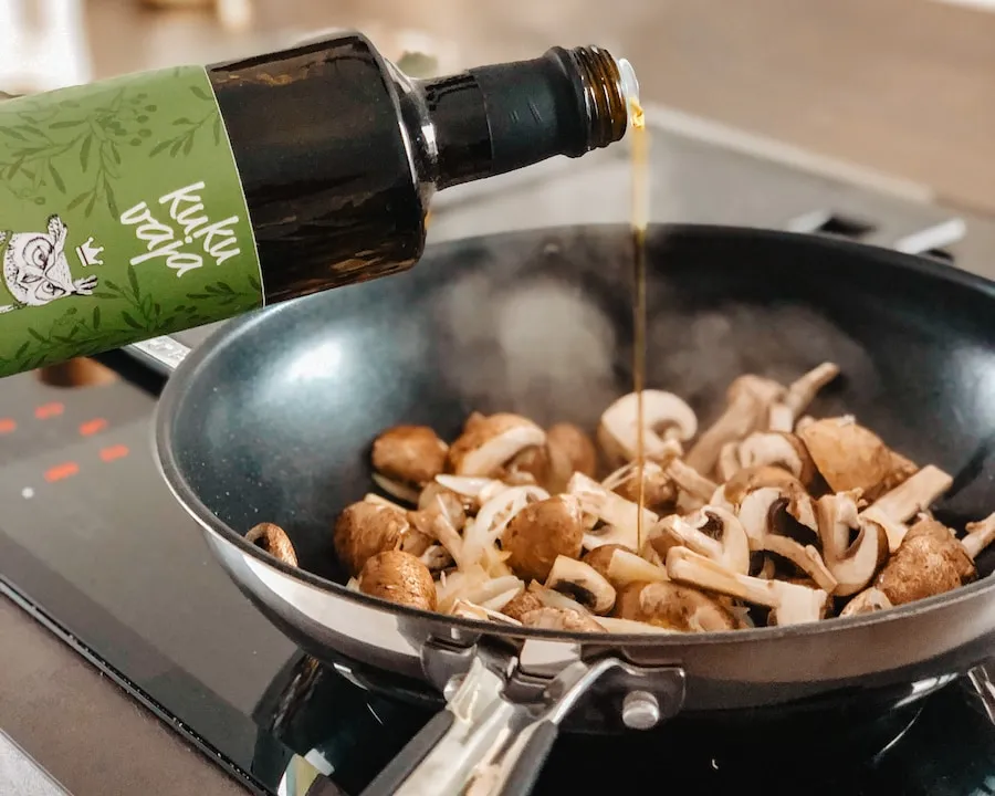 A stainless steel pan cooking mushrooms on an induction cooktop