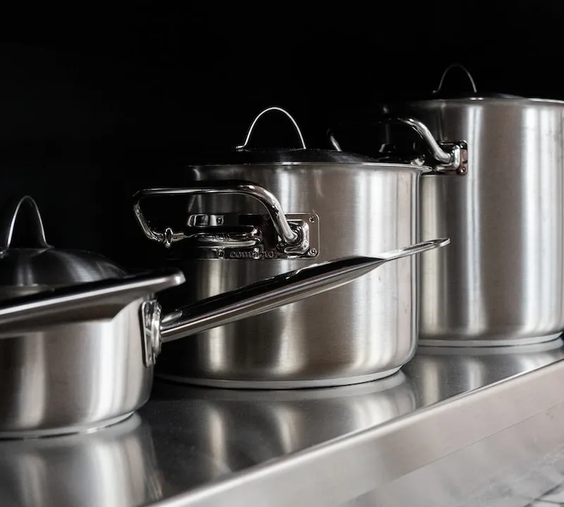 Stainless steel saucepans and stockpots arranged on a dark counter