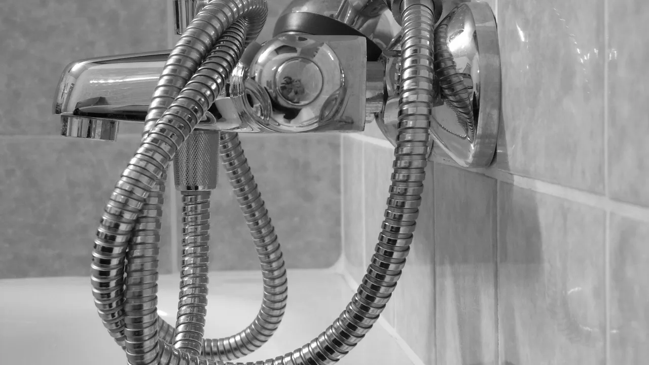 Stainless steel shower head running in a tiled shower