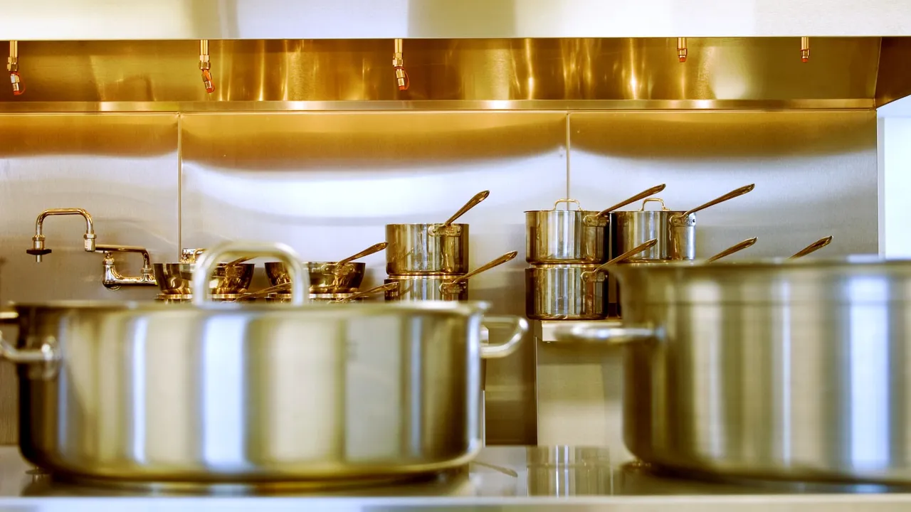 Rows of stainless steel saucepans in a commercial kitchen
